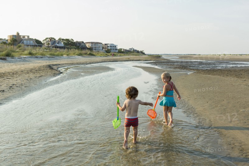 Caucasian brother and sister carrying nets on beach
