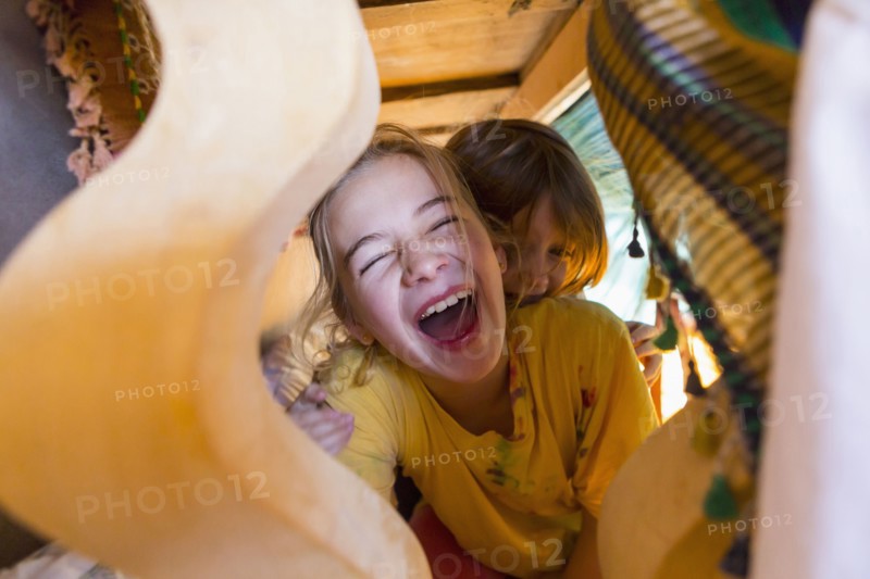 Caucasian brother and sister laughing under table