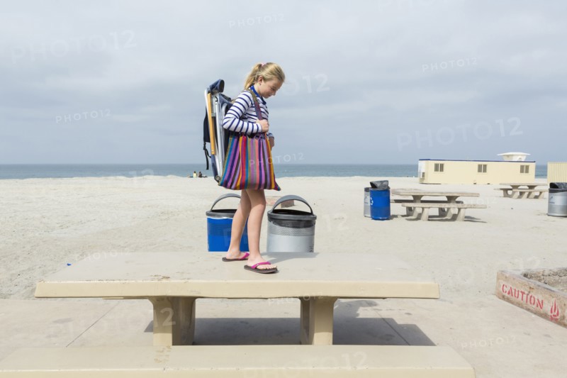 Caucasian girl standing on picnic table at beach