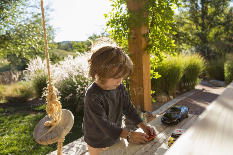 Caucasian boy playing with toy cars on patio