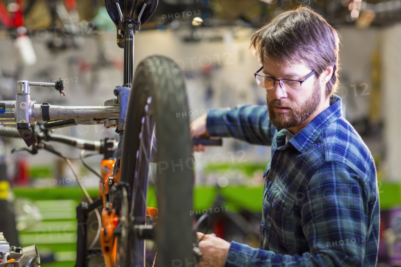 Caucasian man repairing bicycle in shop