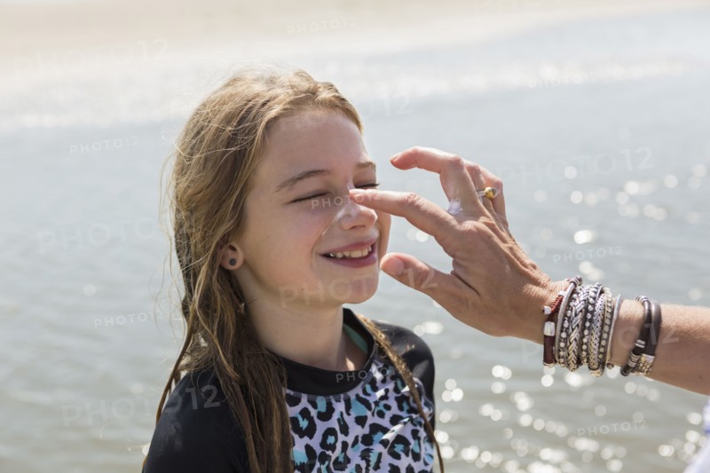 Caucasian mother applying sunblock to nose of daughter