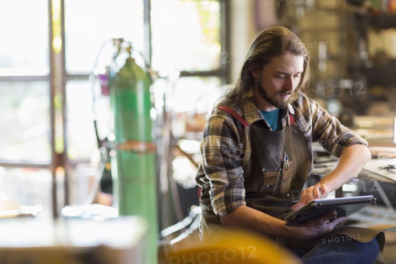 Caucasian man reading a digital tablet in workshop
