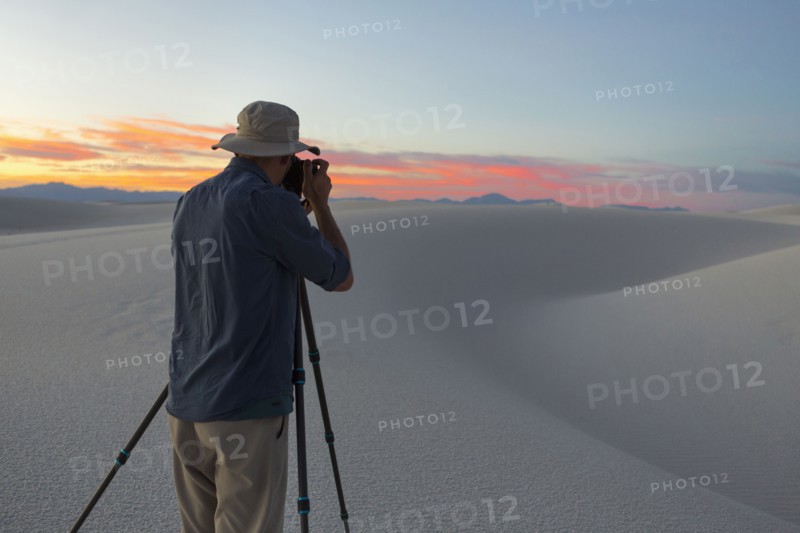 Caucasian man photographing desert at sunset
