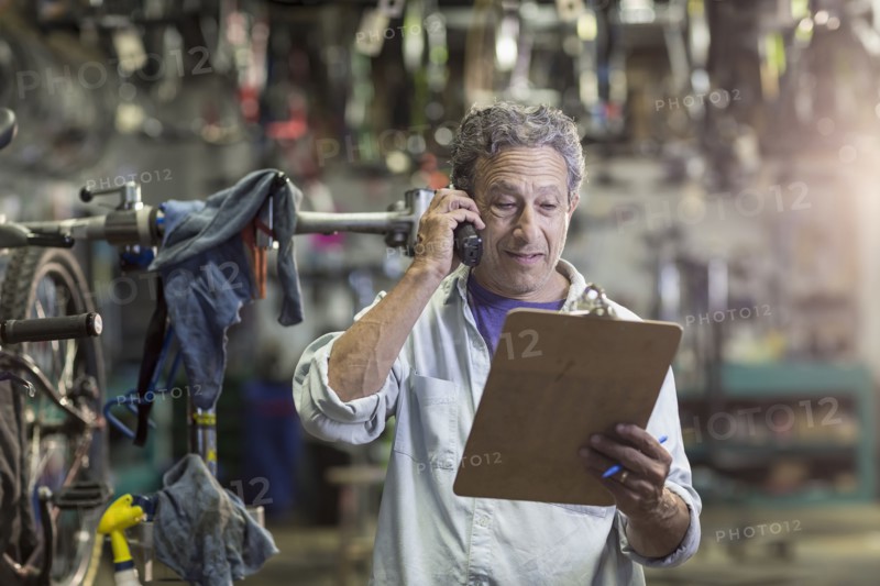 Caucasian man in bicycle shop talking on telephone