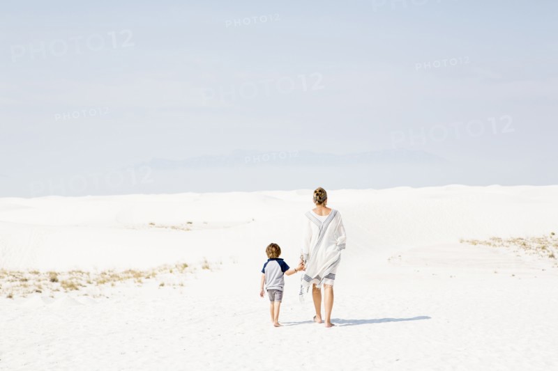 Caucasian mother and son walking in sand