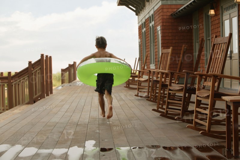 Young boy wearing inner tube on wooden deck