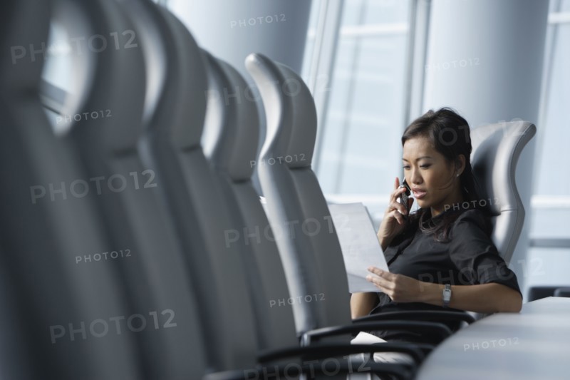 Asian businesswoman using cell phone in conference room