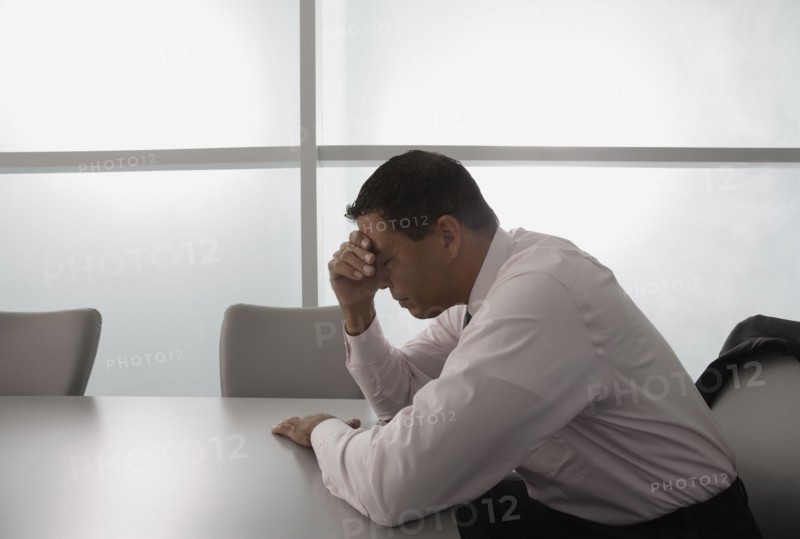 Hispanic businessman with head in hand