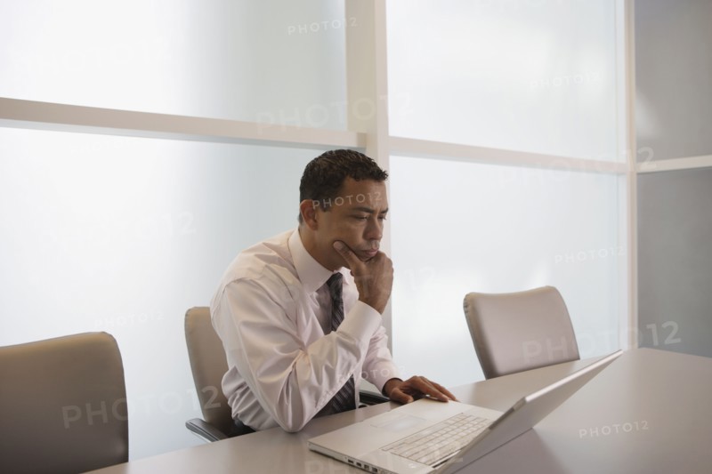 Hispanic businessman looking at laptop