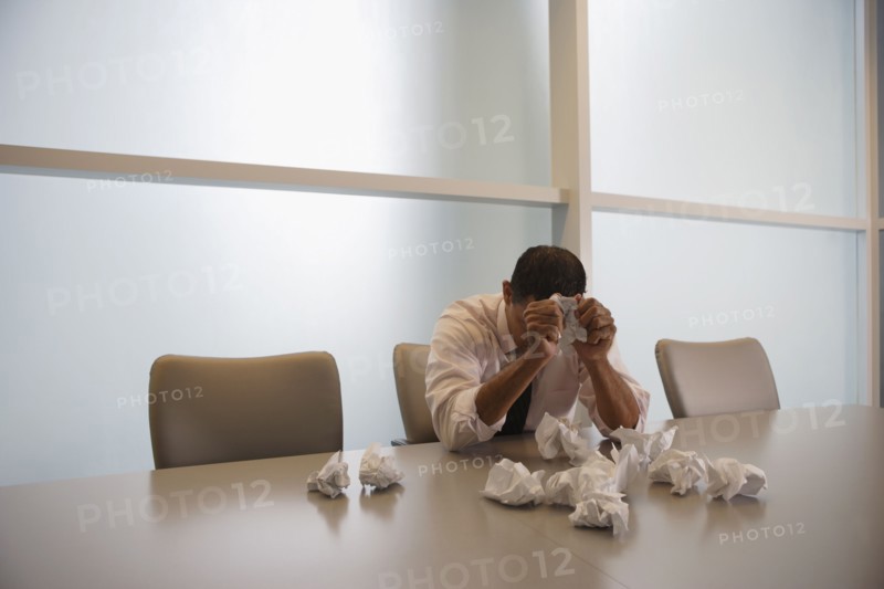 Hispanic businessman next to pile of crumpled paper