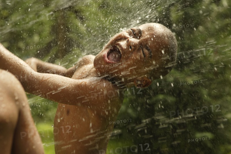 African American boy playing in sprinkler