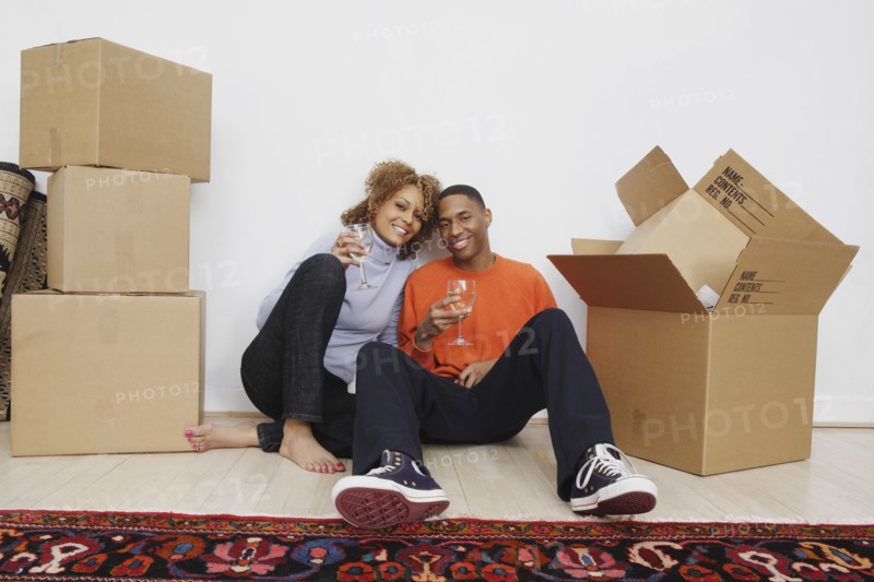 African couple with wine next to moving boxes