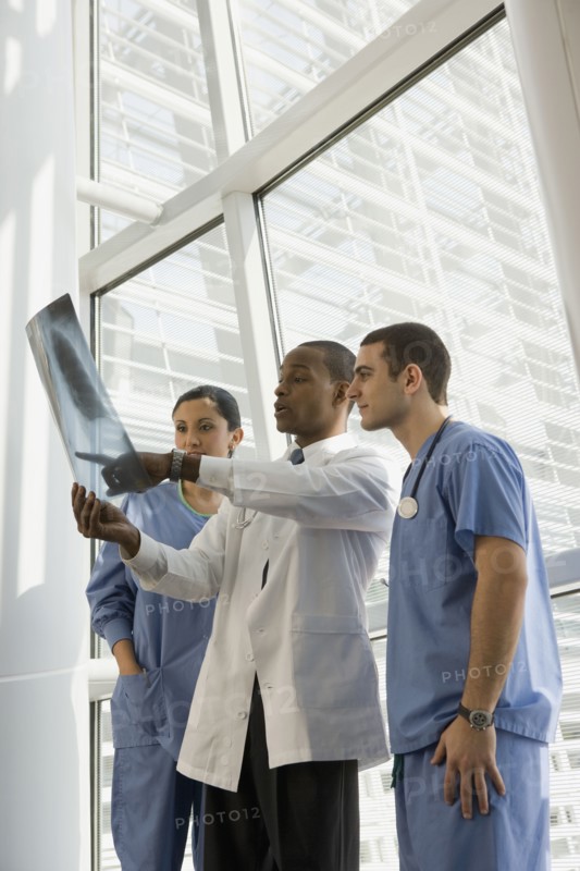 Multi-ethnic doctor and nurses reviewing x-ray by window