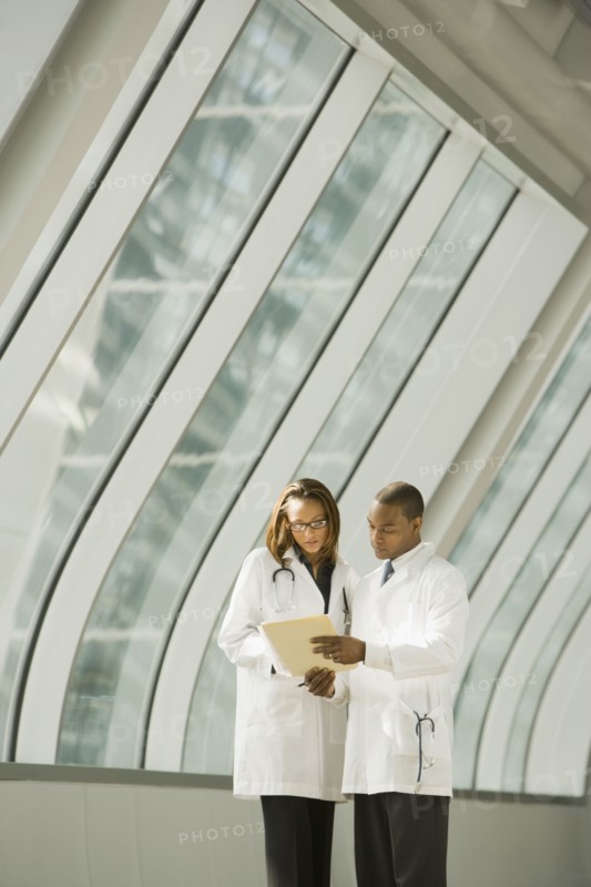 African doctors reviewing medical chart in corridor