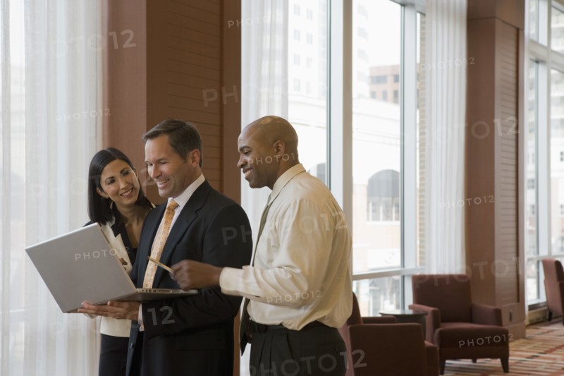 Multi-ethnic business people working on laptop in corridor