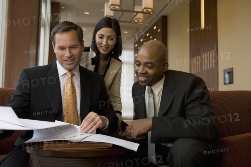 Multi-ethnic business people reviewing paperwork in lobby