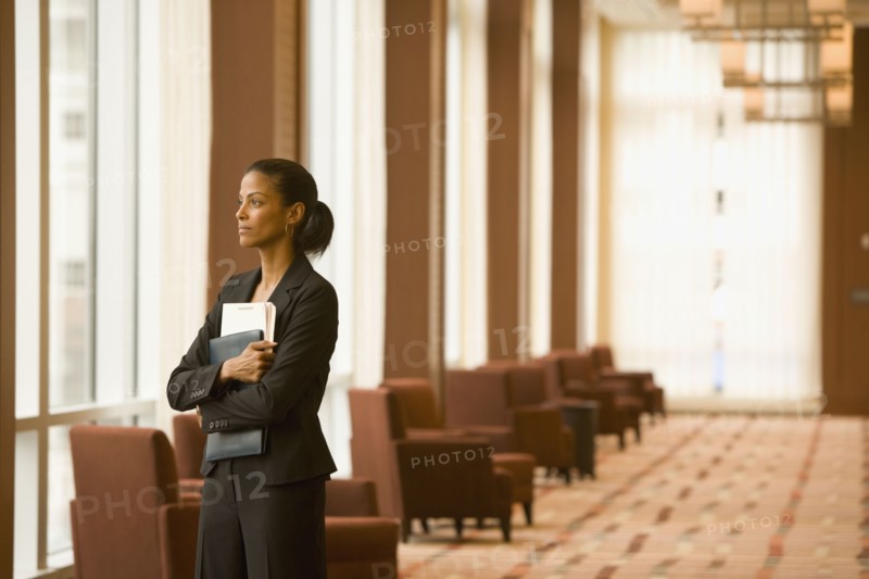 African businesswoman holding paperwork in hotel lobby