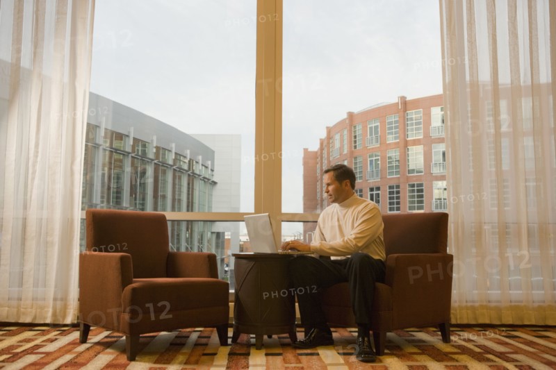 Businessman working on laptop in hotel waiting area