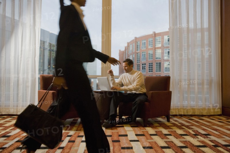 Businessman working on laptop in waiting area near window