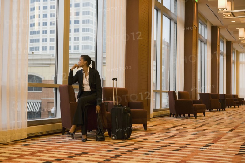 African businesswoman with suitcase looking out window