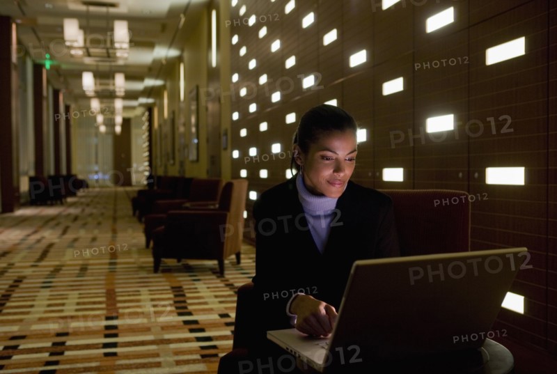 African businesswoman working on laptop late in lobby
