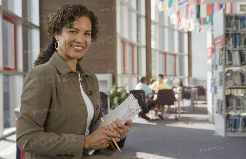 Hispanic woman holding paperwork in library