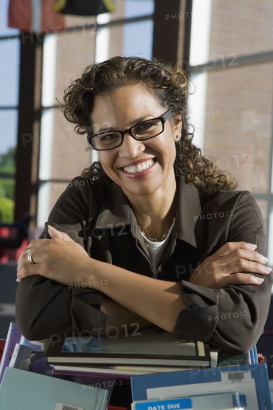 Hispanic librarian leaning on stack of books