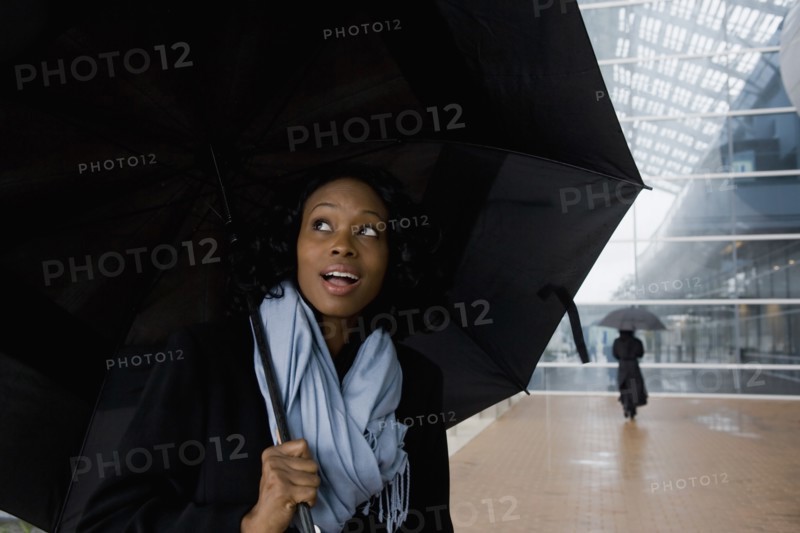 African businesswoman holding umbrella in rain