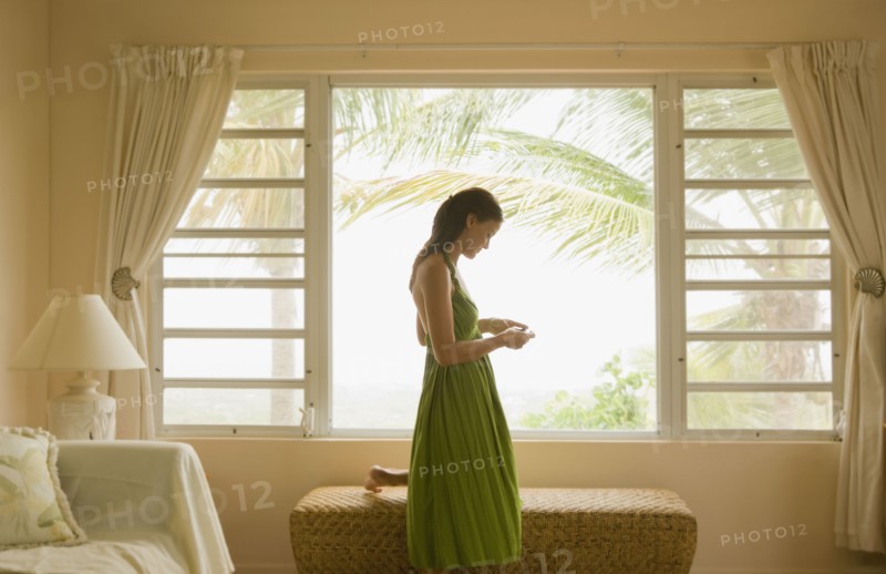 Mixed race woman looking at cell phone near window