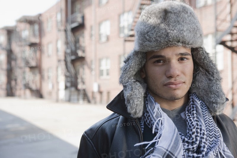 Mixed race man wearing fur hat on urban street