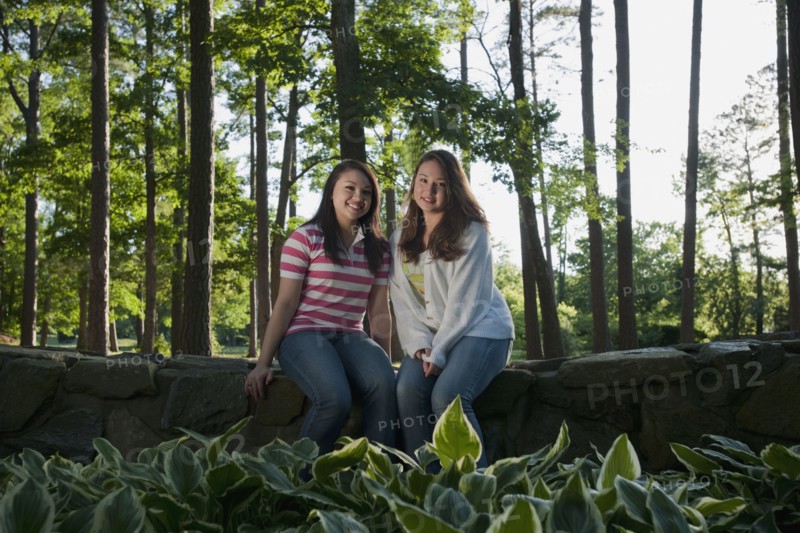 Mixed race friends sitting on stone wall