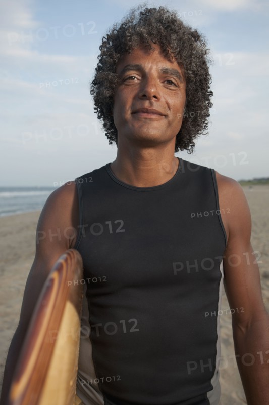 Mixed race man holding surfboard on beach