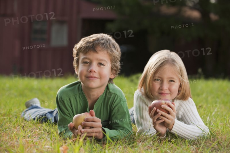 Mixed race brother and sister laying in grass