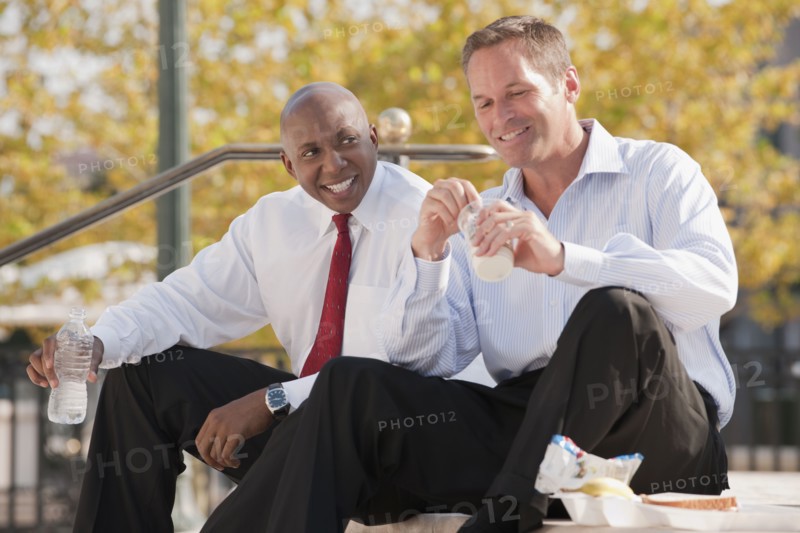 Businessmen eating lunch on steps