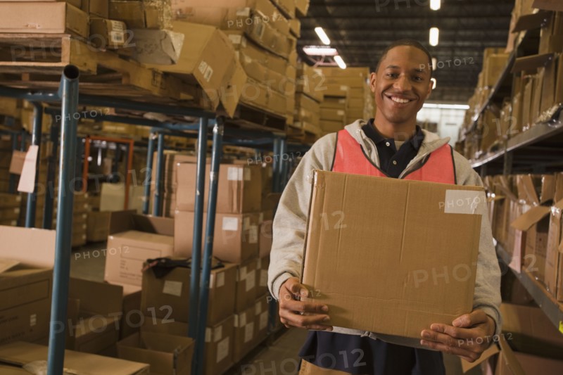 Black man carrying box in warehouse