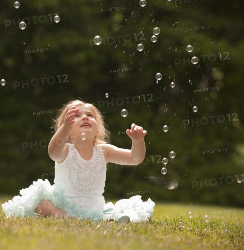 Caucasian girl watching floating bubbles