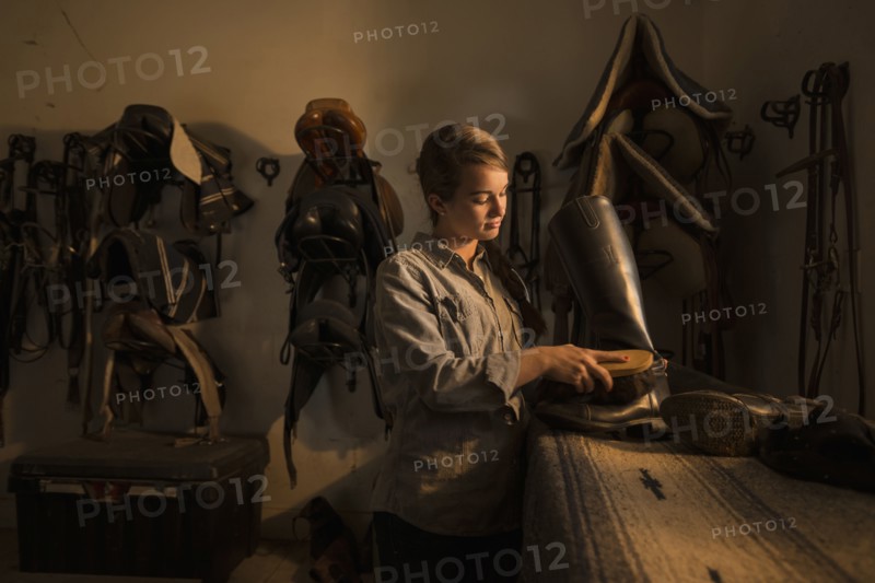Caucasian girl caring for boots in horse stable