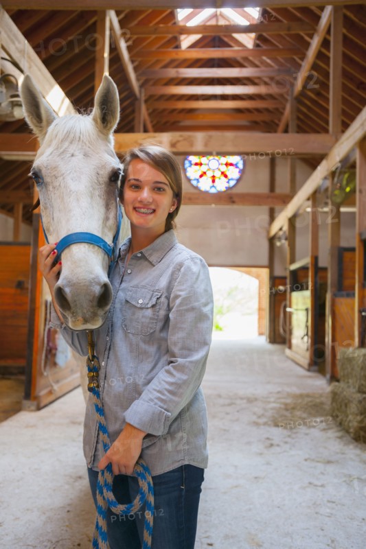Caucasian girl smiling with horse in stable