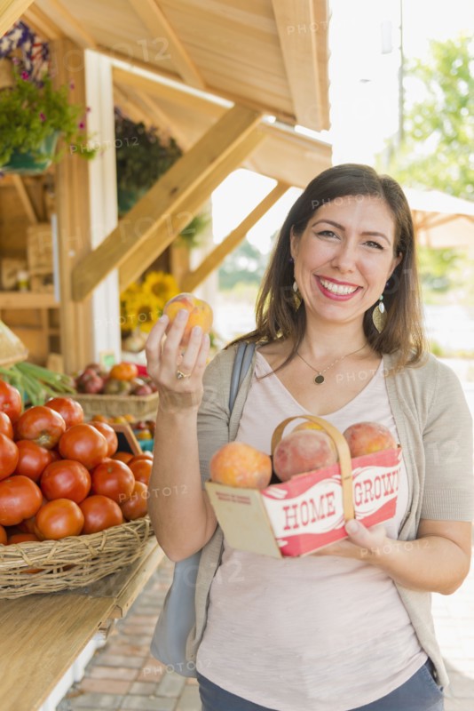 Hispanic woman holding produce at farmers market