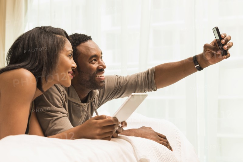 Couple taking selfie on bed
