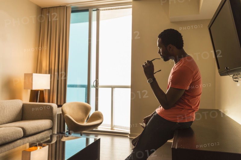 Black man leaning on credenza in living room