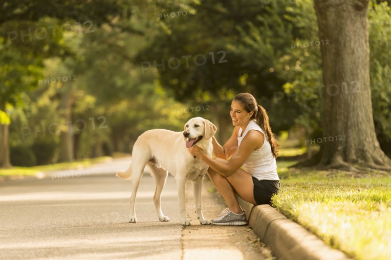 Caucasian woman petting dog on neighborhood street