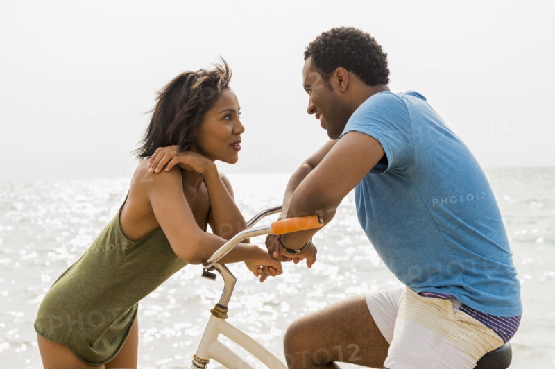 Couple talking on beach with bicycle