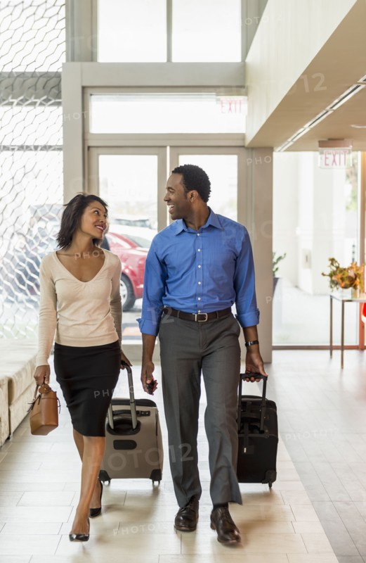 Business people rolling luggage in hotel lobby