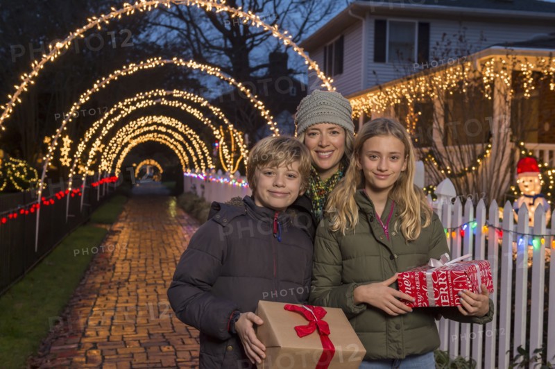Caucasian family holding Christmas gifts on sidewalk