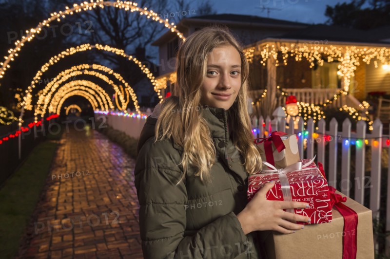 Caucasian girl holding Christmas gifts on sidewalk