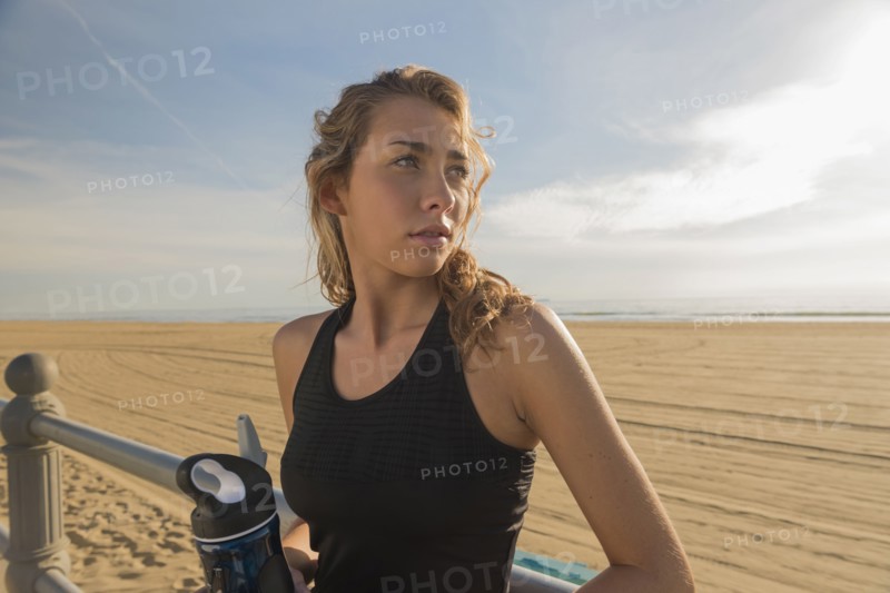 Caucasian teenage girl leaning on railing at beach