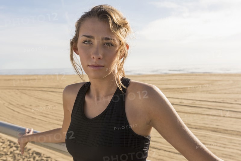 Caucasian teenage girl leaning on railing at beach