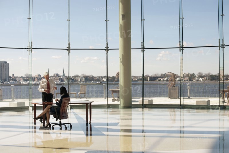 Business people working in large office with glass wall